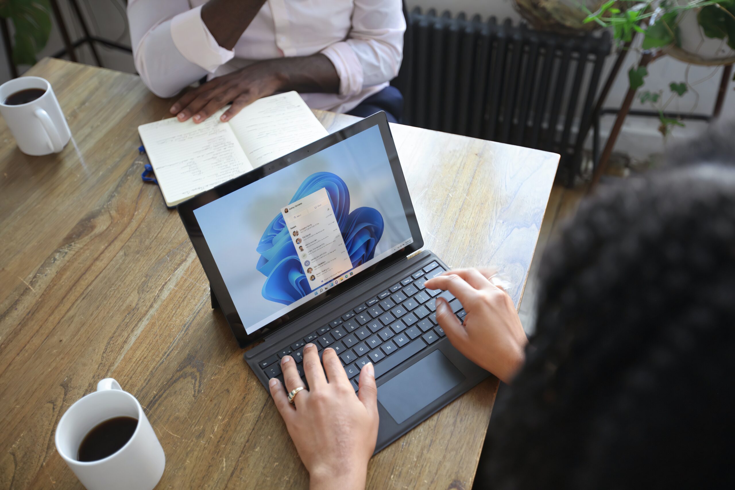Workspaces-a-VPN-More-Learn-the-Newest-Microsoft-Edge-Features-scaled.jpg Overhead view of two people at a table working with a Microsoft laptop and notebook